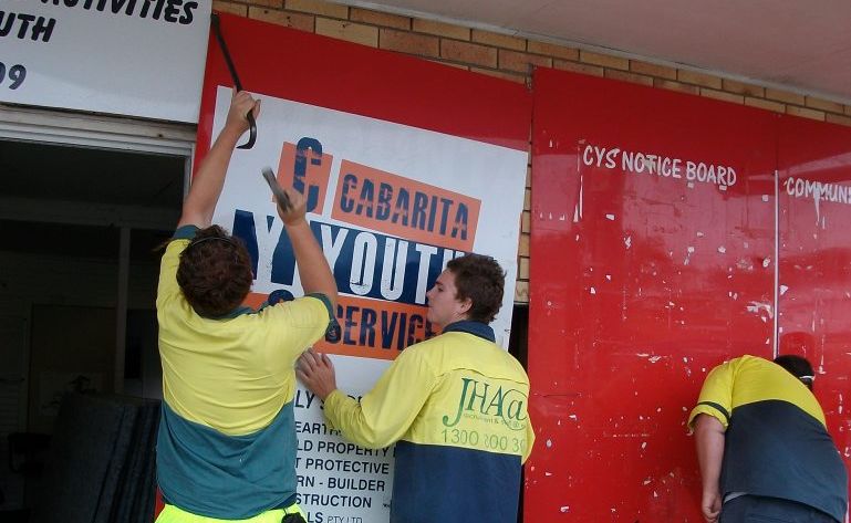 Workers removing the Cabarita Youth Service's signage from the building.